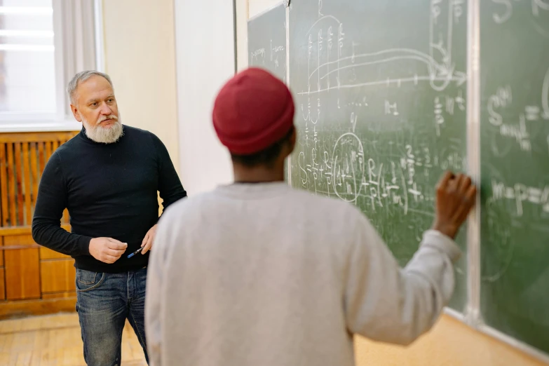 two men are standing in front of a chalkboard