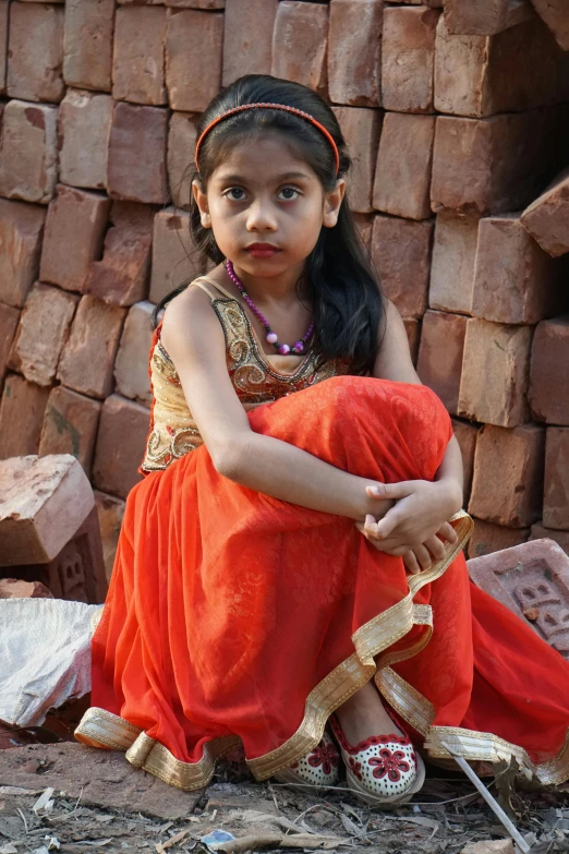 young indian girl sitting on bricks with knife in her hand