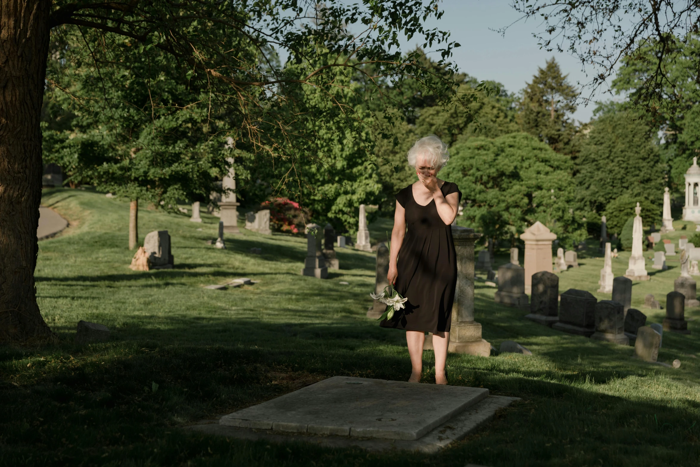 an old woman standing in a cemetery