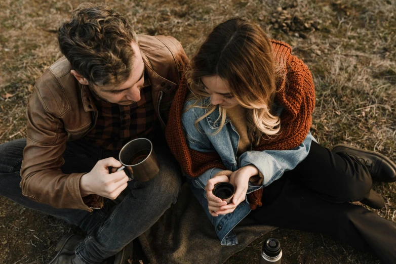 two people sitting down on grass and looking at the reflection in their mirrors