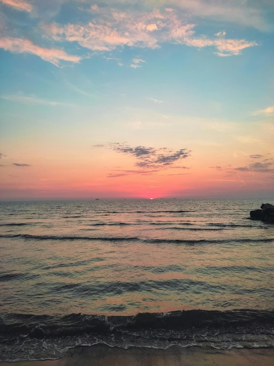 a person on the beach with a surfboard at sunset