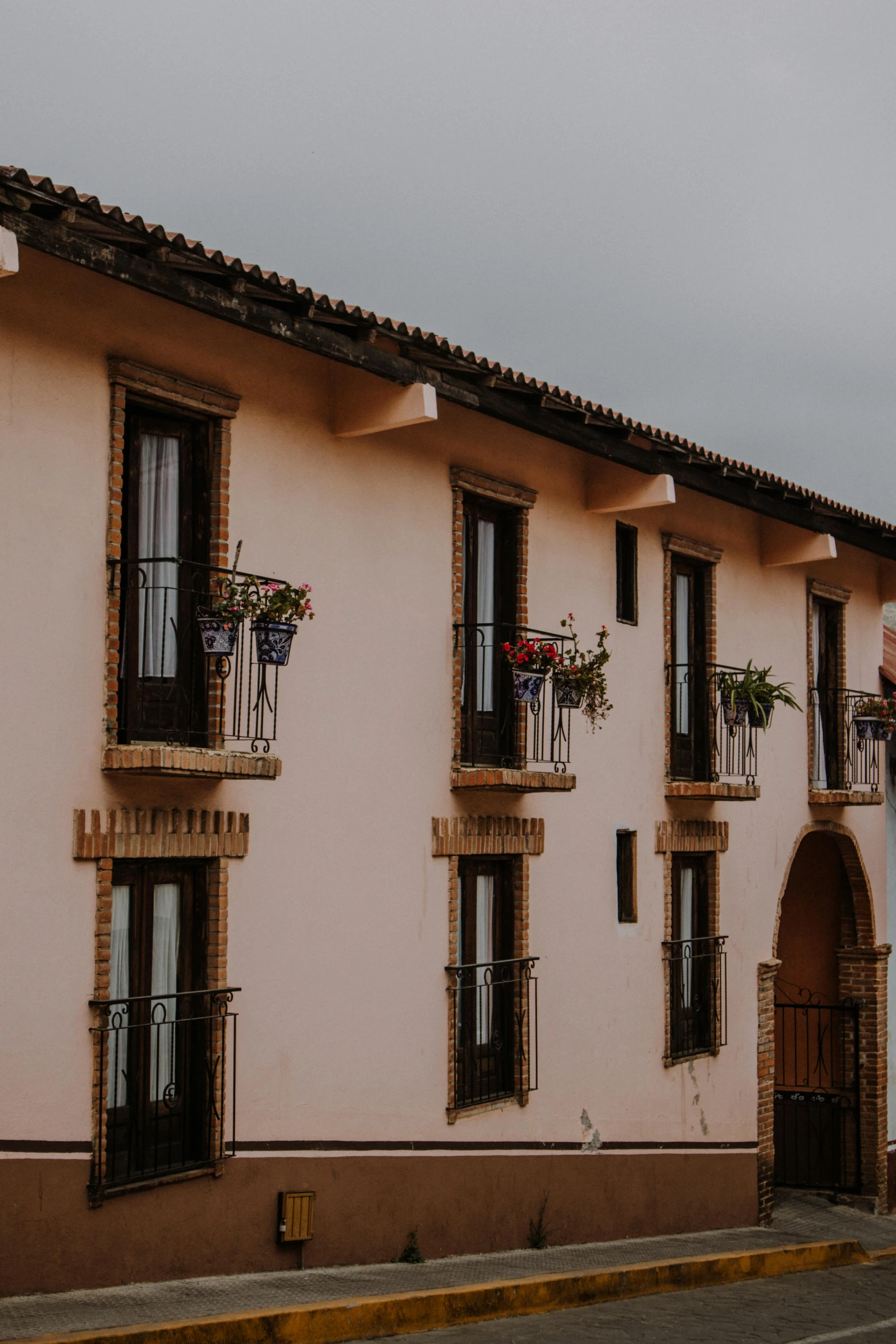 a pink building that has some flowers hanging from the windows