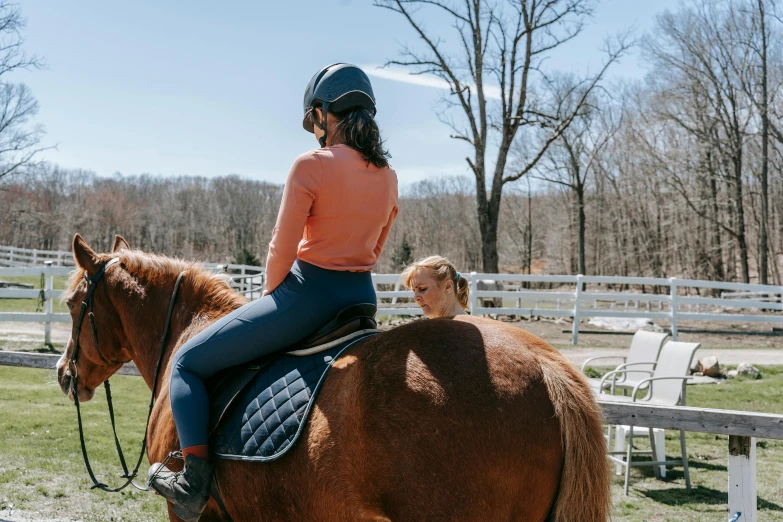 a woman wearing a helmet is riding a brown horse