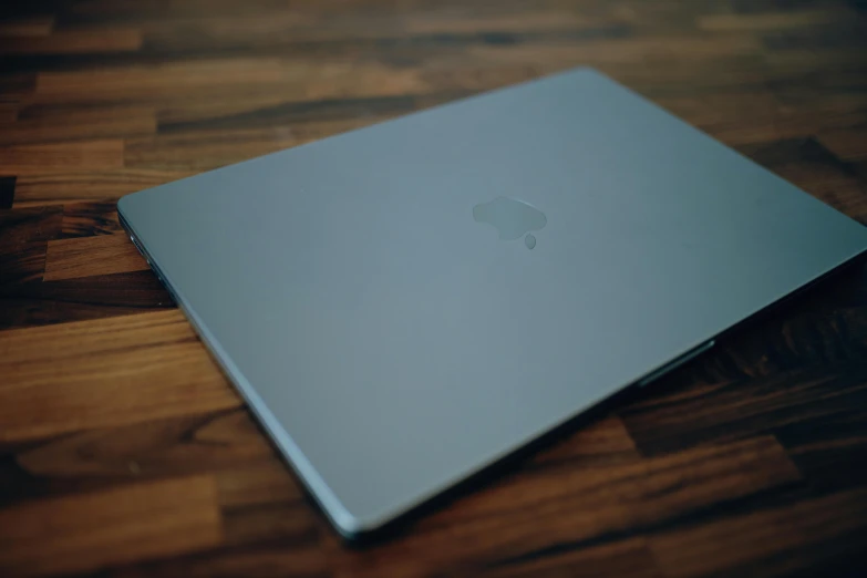 an apple laptop on a wooden surface in a room