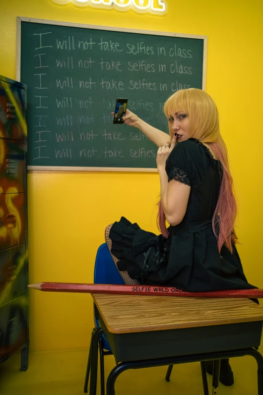 a woman sitting in a school classroom looking at her phone