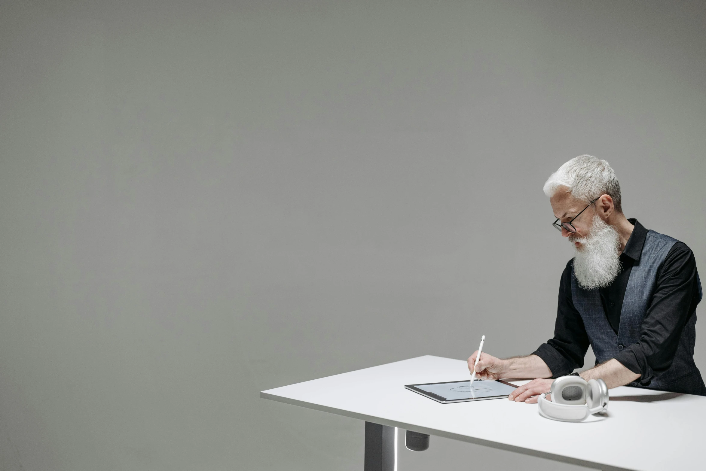 an older man sits at a table writing on paper