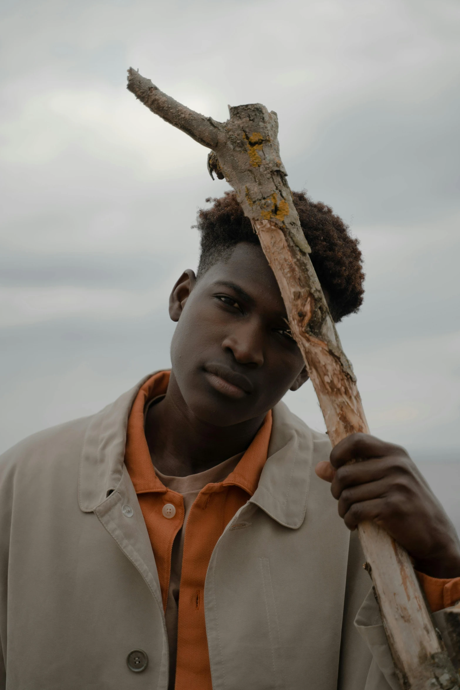 a man wearing an orange tie stands with a cross on his shoulder