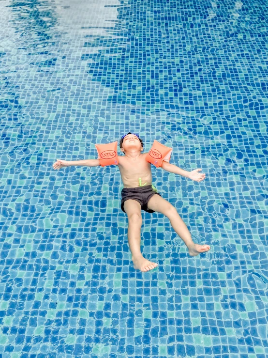 a  swims in the pool while wearing large life vests