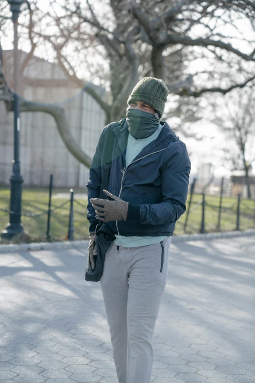 man walking down the street in winter wear using his cellphone