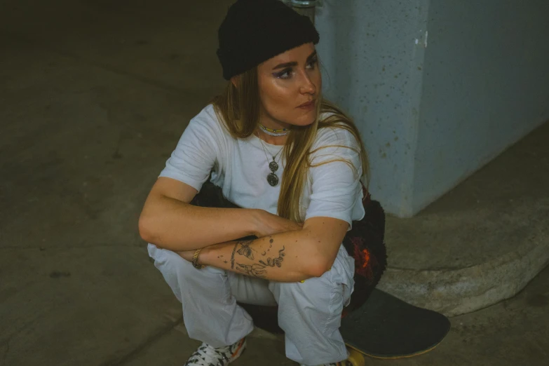 girl with her hands clasped sitting on a skateboard