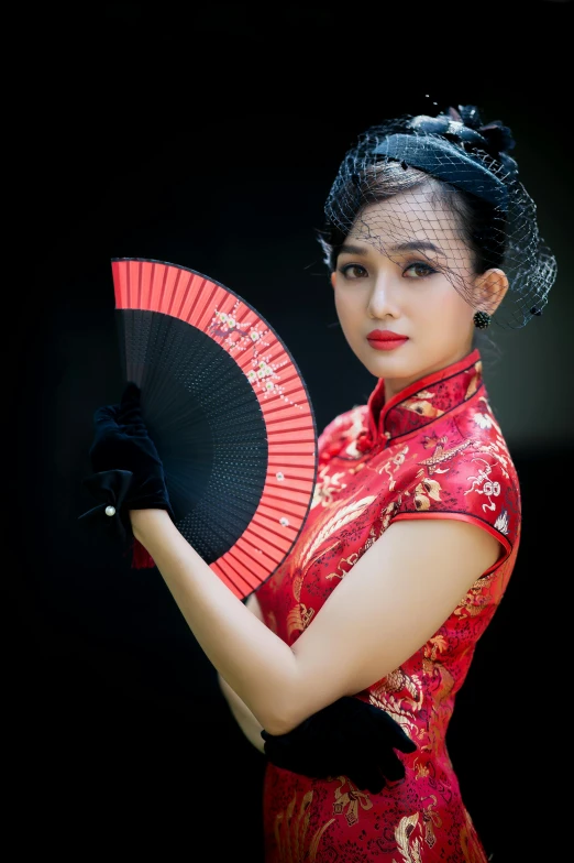 a woman wearing a chinese dress holding a black and red fan