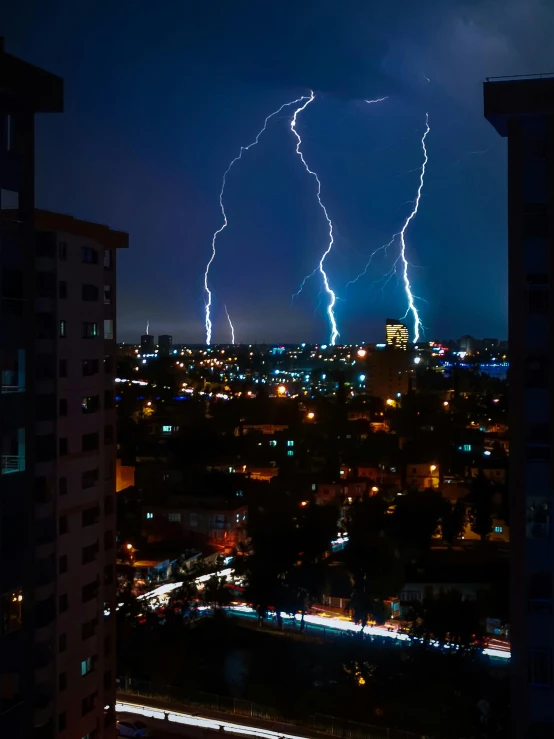 several lightning bolts over a city in the night