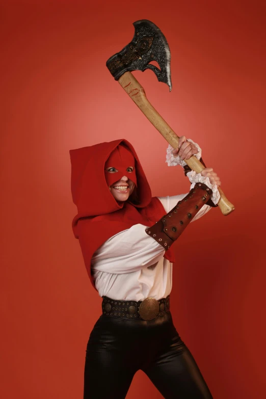 woman dressed as a red riding hood holding up an axe