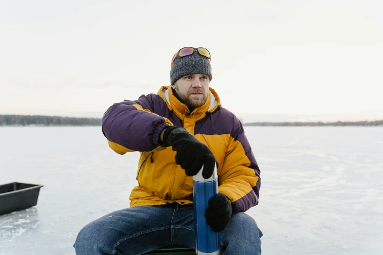 a man sitting in the ice holding a blue object