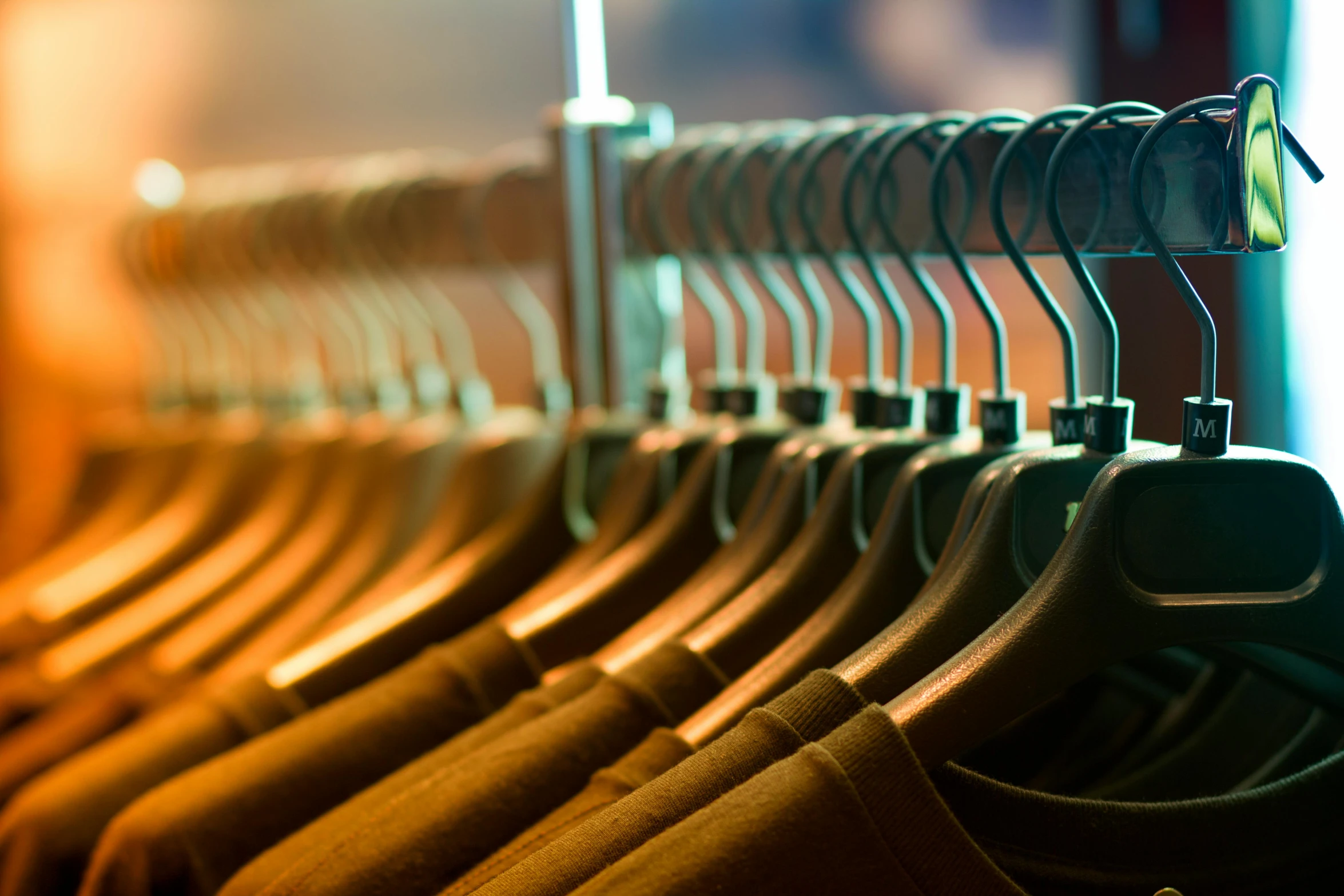 a rack full of shirts hanging on metal bars