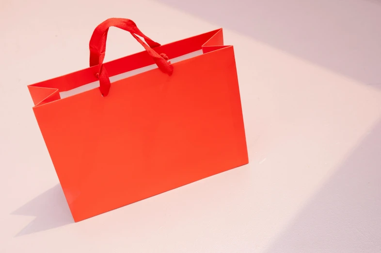 a shopping bag with red ribbon hanging on a wall