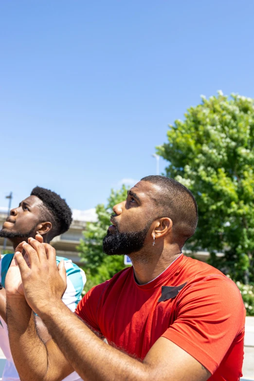 two young men standing together and one has his hands up to his mouth