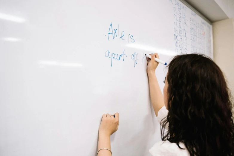 the woman writes on the whiteboard and writes numbers