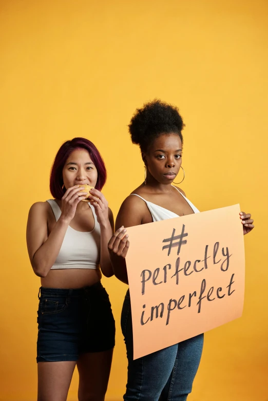 two s hold up signs that read perfectly imperfect