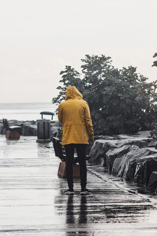 the man is carrying his suitcase under the coat in the rain