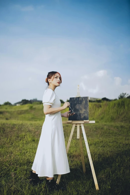 girl in white dress holding a paint brush painting a picture