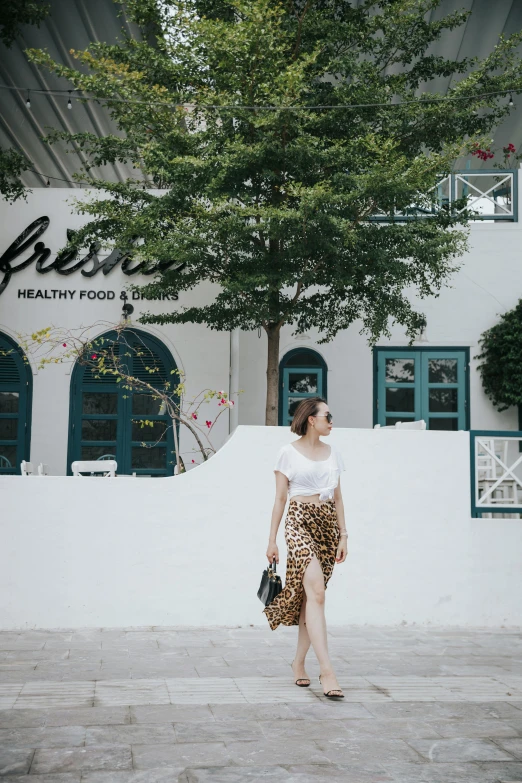 a girl standing next to a white wall holding a black purse