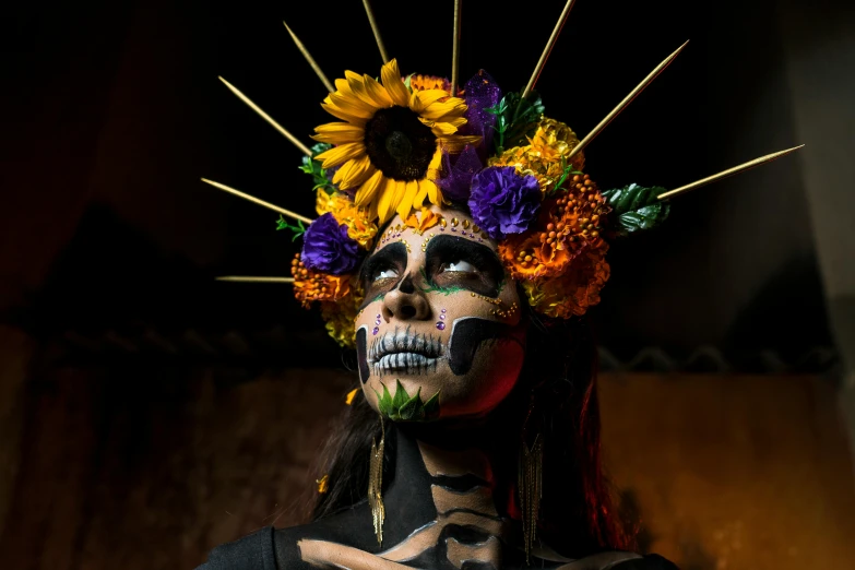 a woman with brightly colored makeup with sunflowers on her head