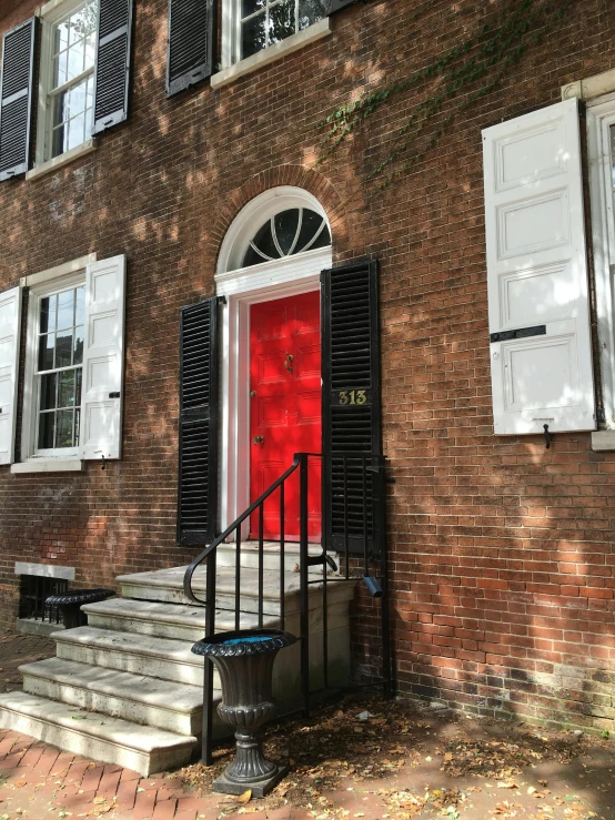 a red door with shutters and a black staircase