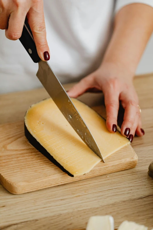 woman slicing cheese with a big knife on the table