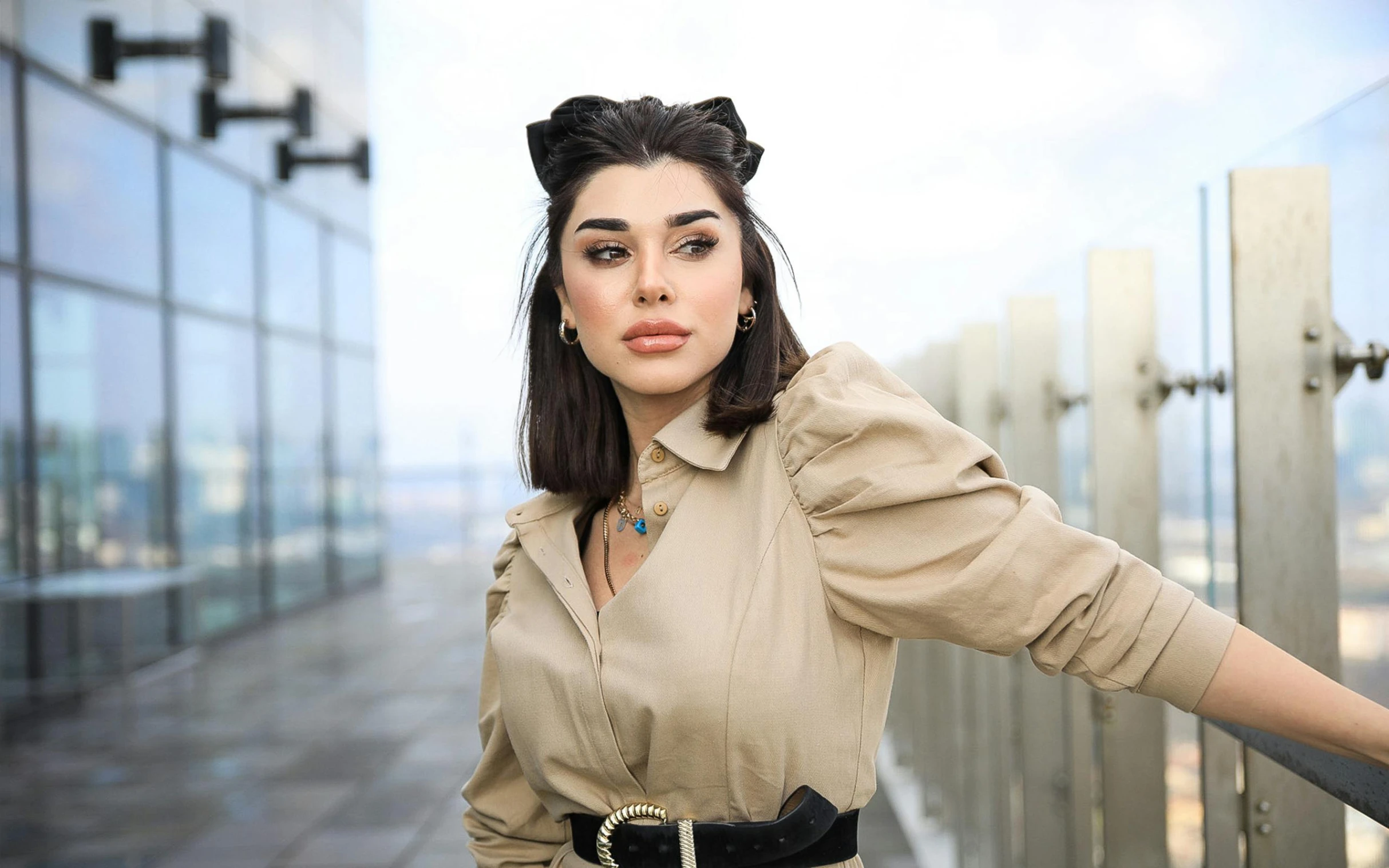 a woman is dressed in a beige top and black belt