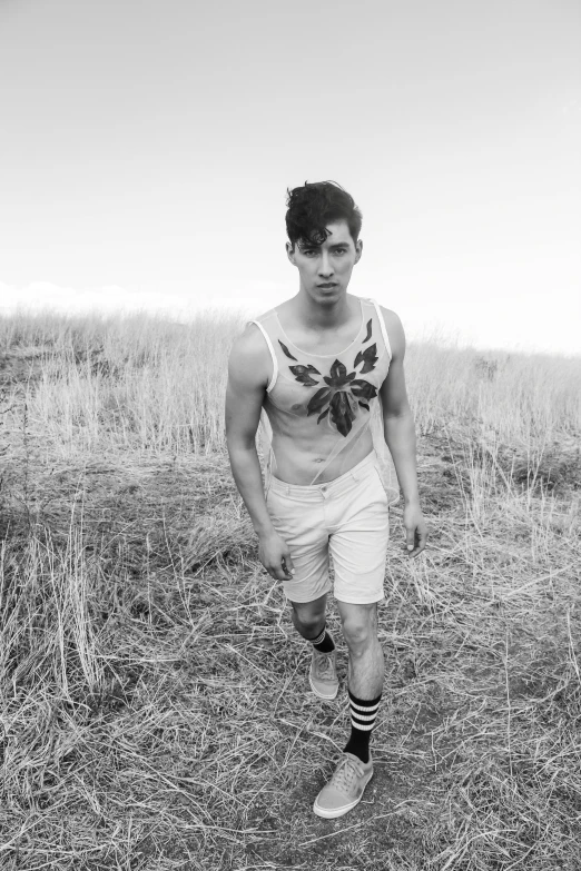 a shirtless young man walking through the dry grass