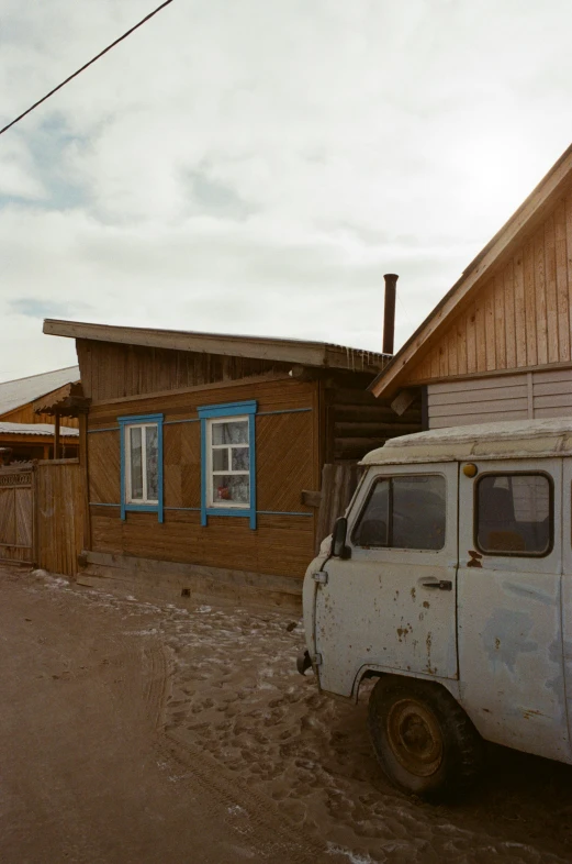 a small white van parked outside of a wooden building