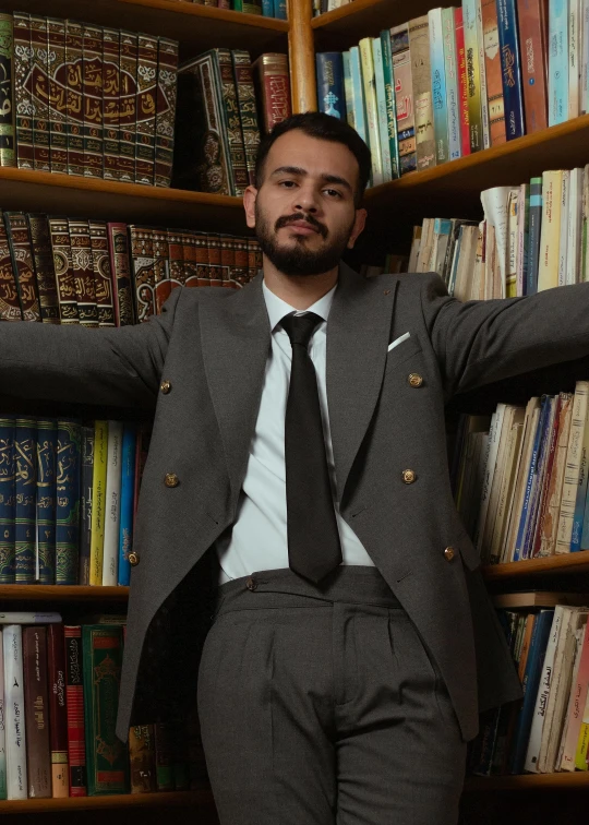 a man posing in front of a liry full of books