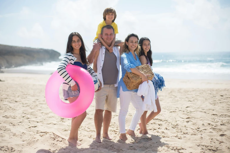 a man with two girls, one holding a child on the beach