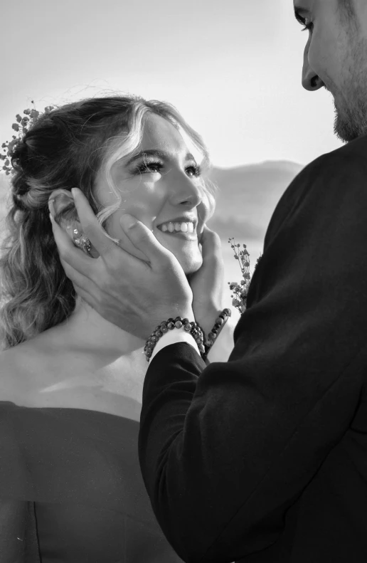 a black and white po of a woman smiling while another man holds his face with one hand