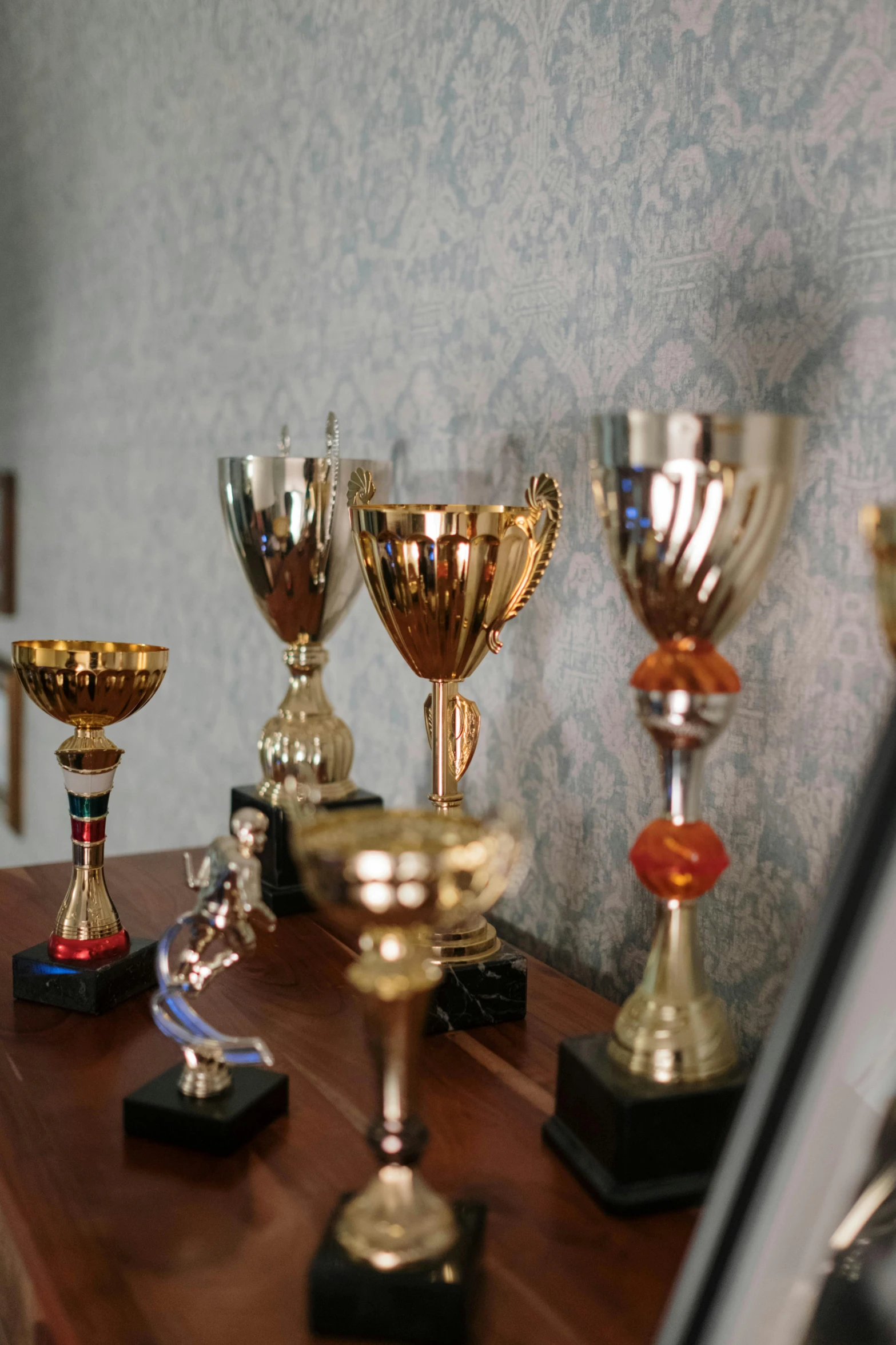 many trophies sit next to each other on top of a wooden desk