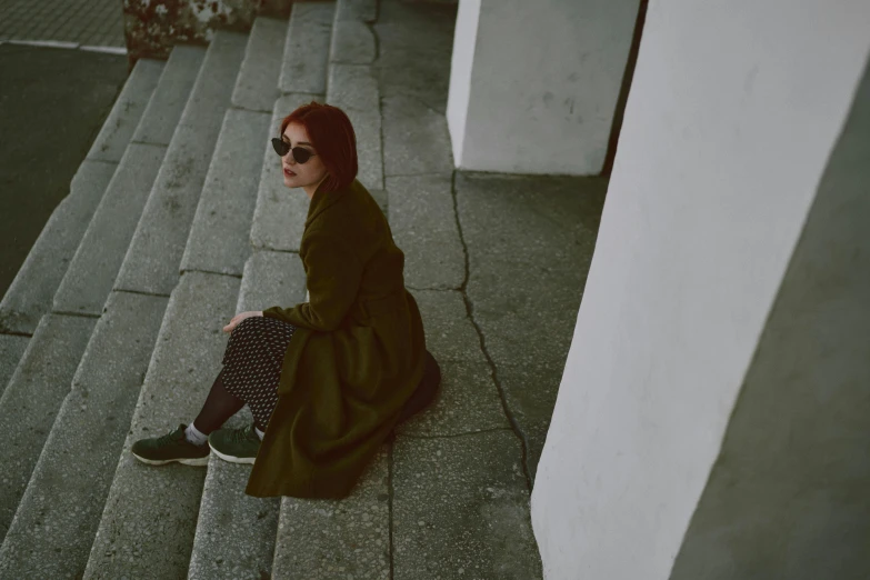 a woman wearing sunglasses sitting on a walkway
