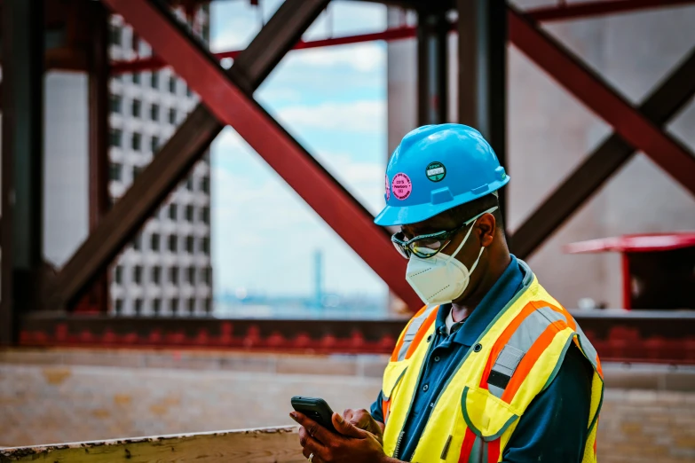 man in hard hat using cellphone wearing safety clothing