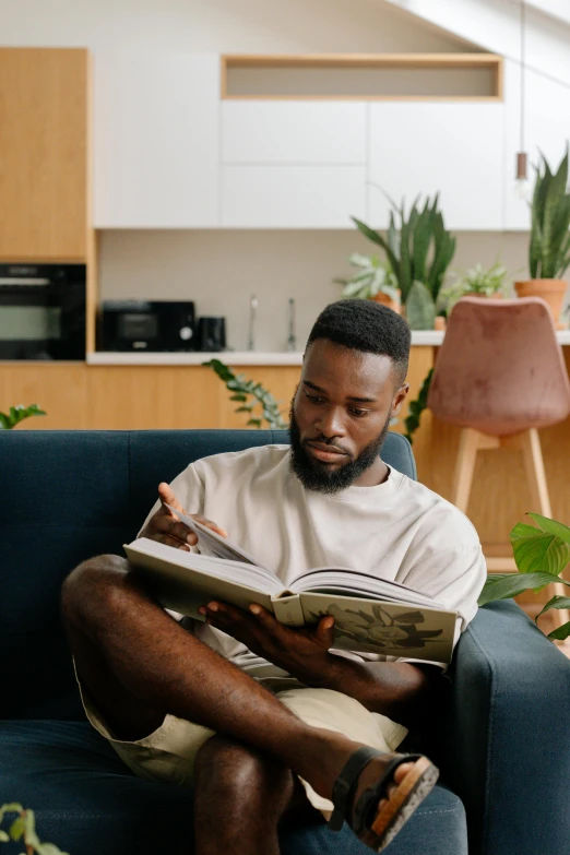 a man reading a book while sitting in a chair