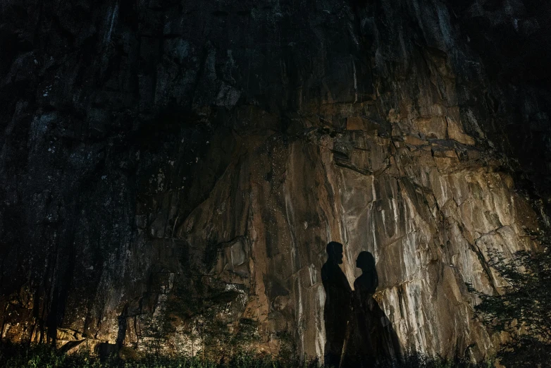 couple standing beneath trees illuminated in dark at night