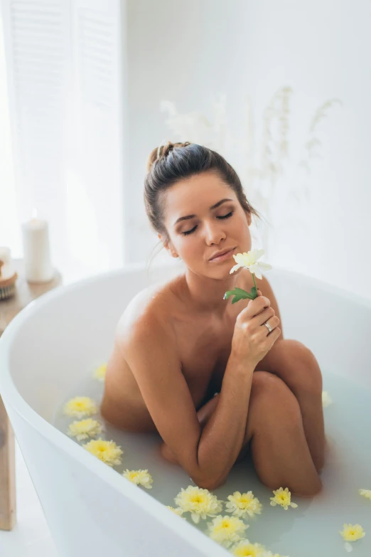 a woman is sitting in a tub with flowers around her