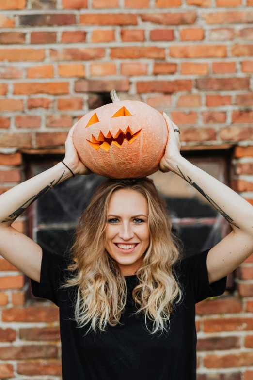 a woman holding up a pumpkin for halloween