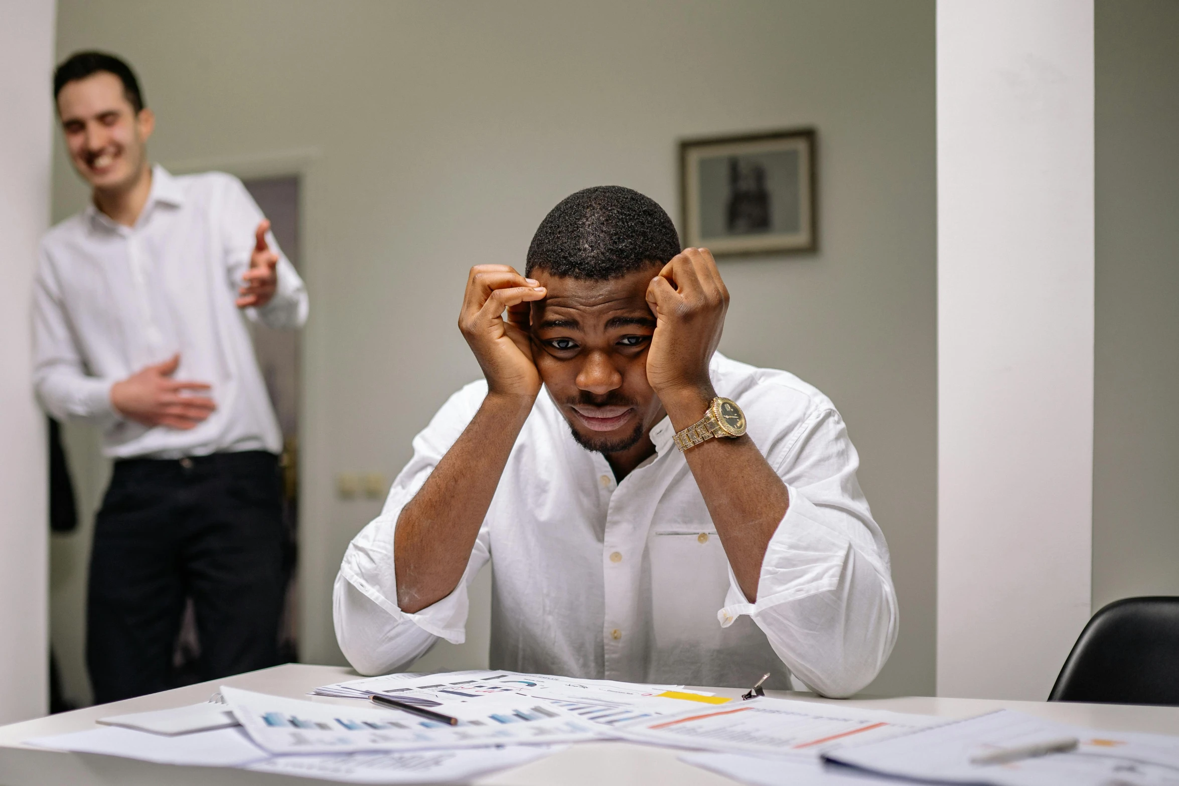 a man in an office holding his head with both hands