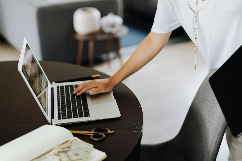 a person standing over a laptop on top of a table