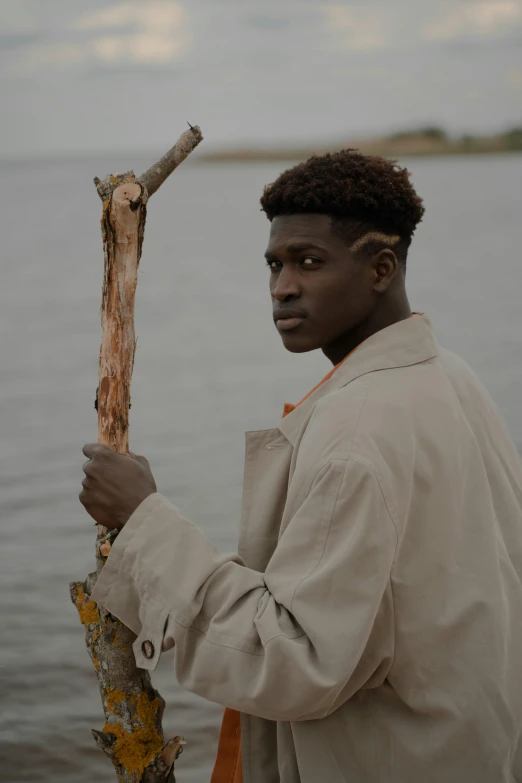 the man is standing near the water holding a stick