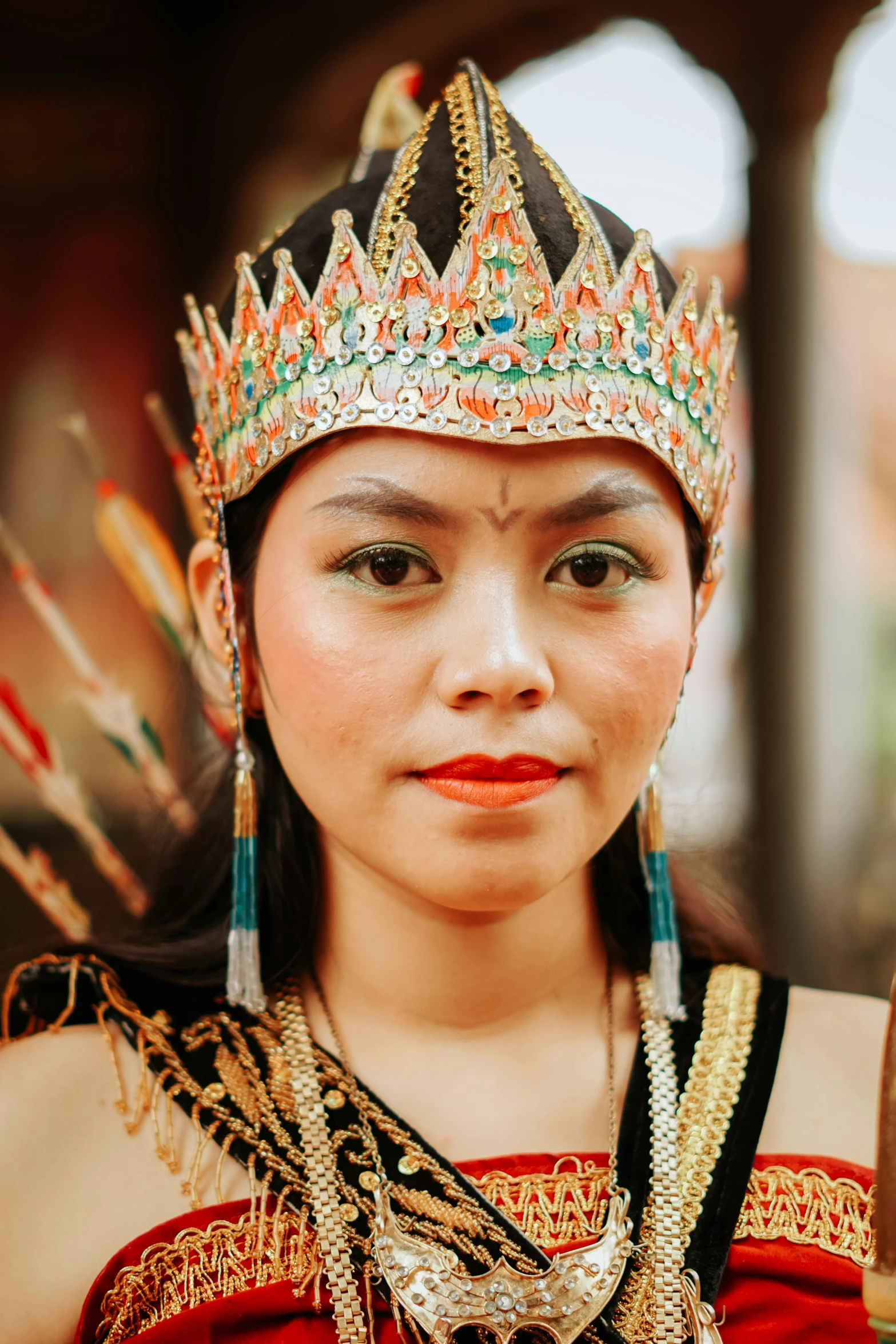 a woman in a red dress is wearing some earrings and has a silver tiara