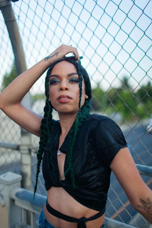 a woman is posing behind a fence and has her hands on her head