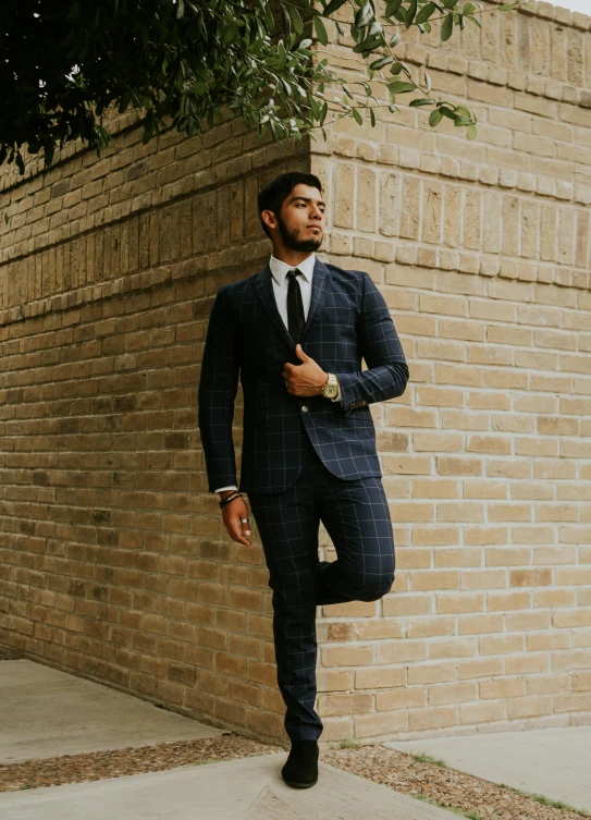 a man in a suit leaning up against a wall