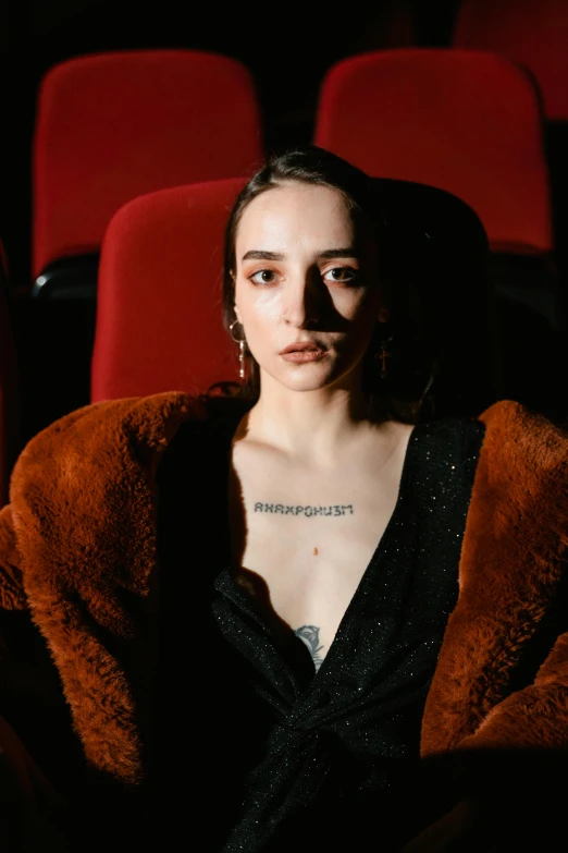 a woman in a black dress sitting in a theater