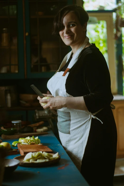 a woman smiles as she stands next to some  up apples